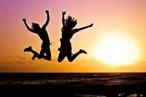 Two Girls Jumping In Sunset With Joy Living A Holistic Life