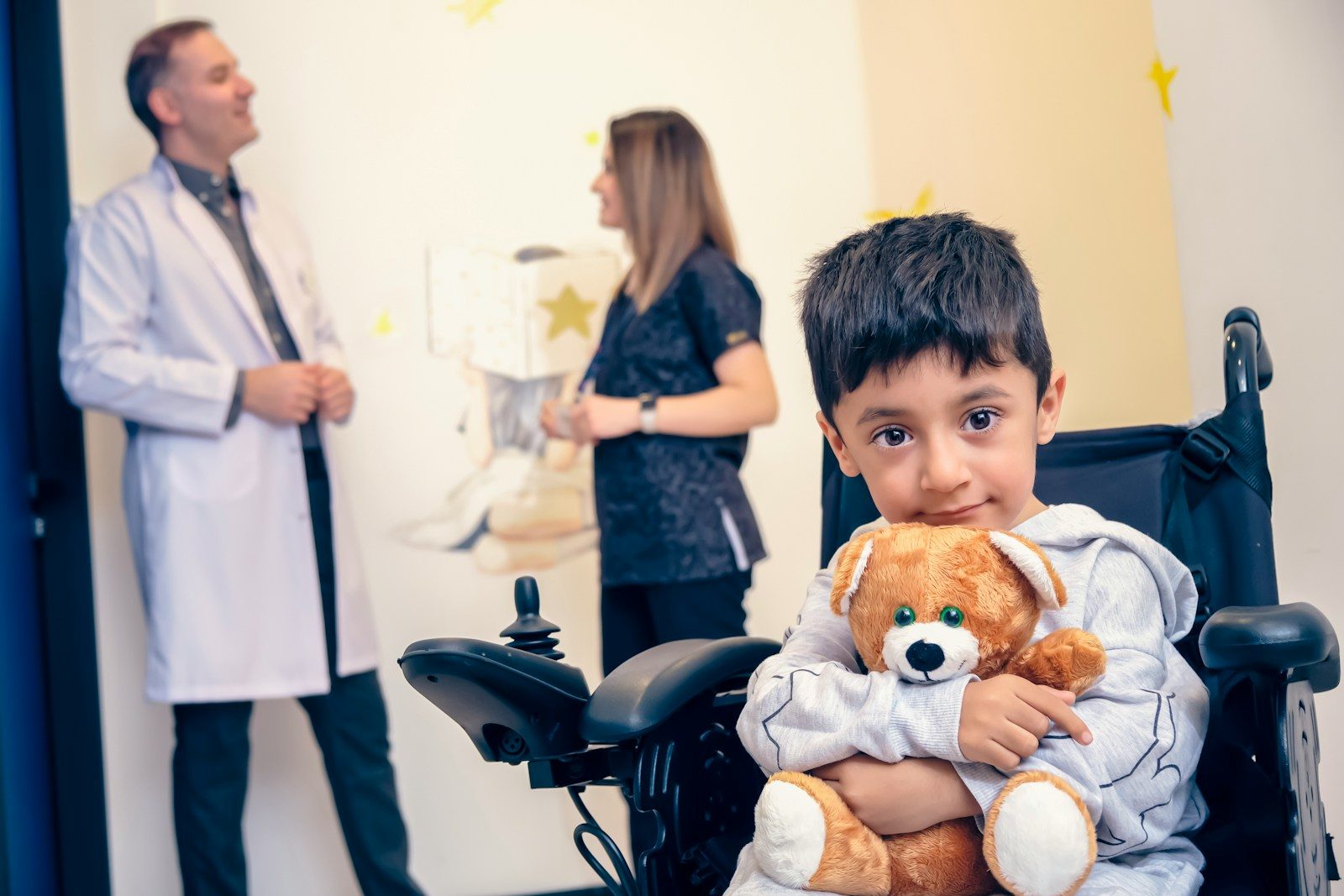 a boy in a wheelchair holding a teddy bear